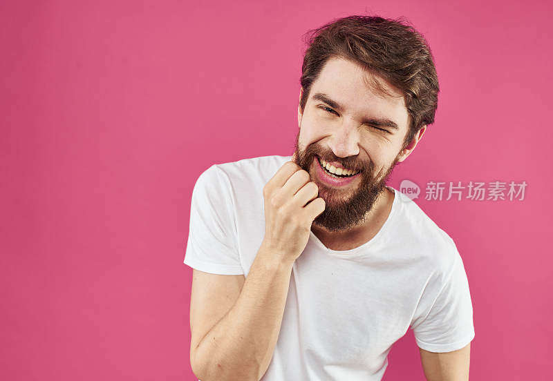 一个留着胡子的快乐的家伙在粉红色的背景上笑着，用手比划着