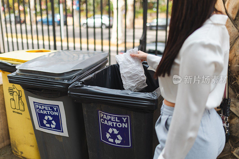 年轻女子在室外的回收箱里扔垃圾