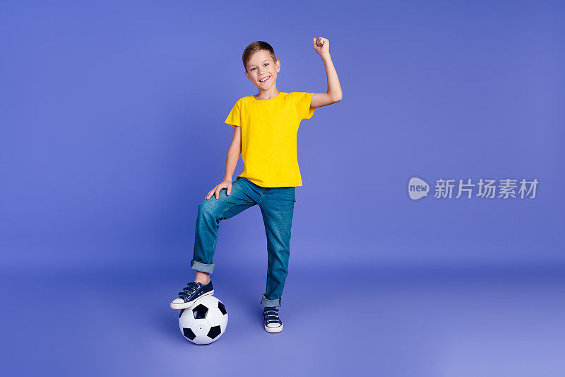 开朗的男孩穿着时尚的衣服踢足球比赛赢得国际足联联赛世界杯冠军的照片孤立的紫色背景