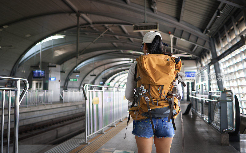 站台上等候的女人，铁路运输概念，旅行者。提着箱子走在火车站站台上的女人。坐火车去度假，站在站台候车。
