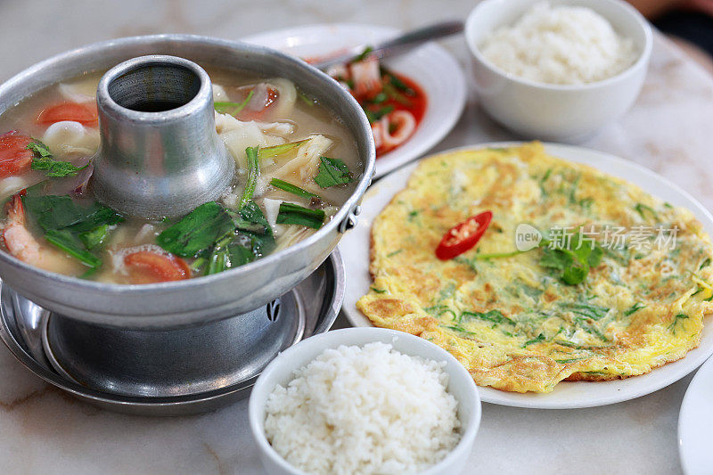 高角度观看正宗的泰国冬阴功美食，配以香喷喷的米饭、煎蛋和鱿鱼沙拉。