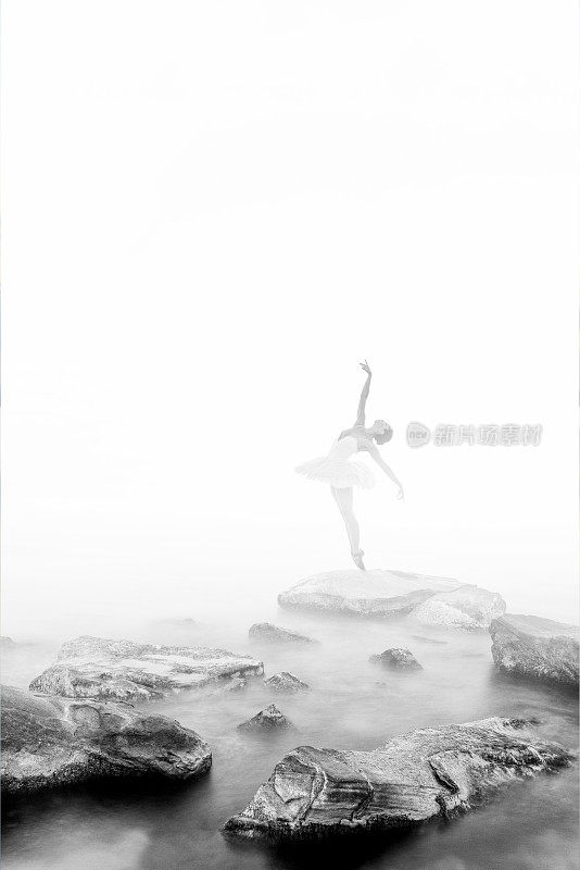 芭蕾舞女演员在雾中的岩石上跳舞