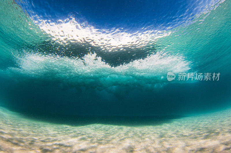 在清澈的海水中，海浪拍打着沙滩，水下的景色一览无余