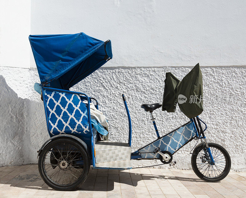 摩洛哥拉巴特，一辆蓝色的三轮车停在一堵白色的墙上