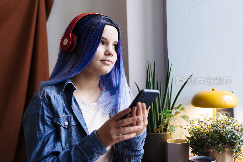 迷人的年轻拉丁裔女孩的肖像，蓝头发，蓝色牛仔衬衫，坐在咖啡馆里使用智能手机，有复制空间。