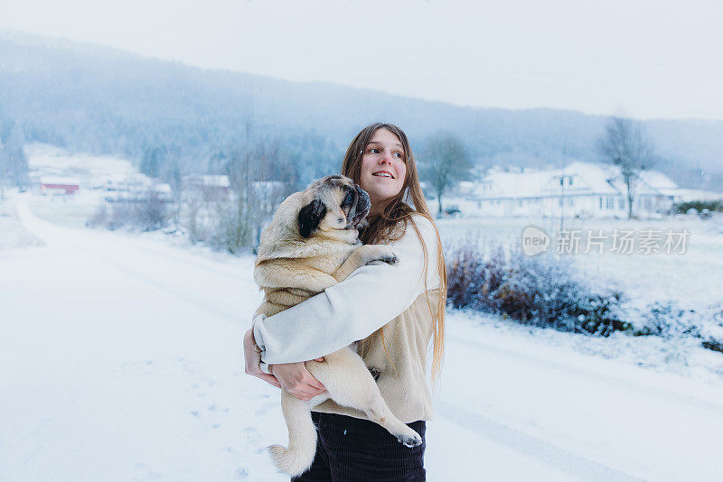 一个快乐的女人在挪威乡下和她的狗一起思考冬天的时光