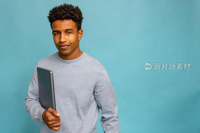年轻的非裔美国人拿着蓝色背景的平板电脑。