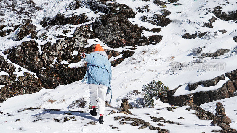 一个女人在寒冷的天气里穿行于白雪覆盖的山林之中