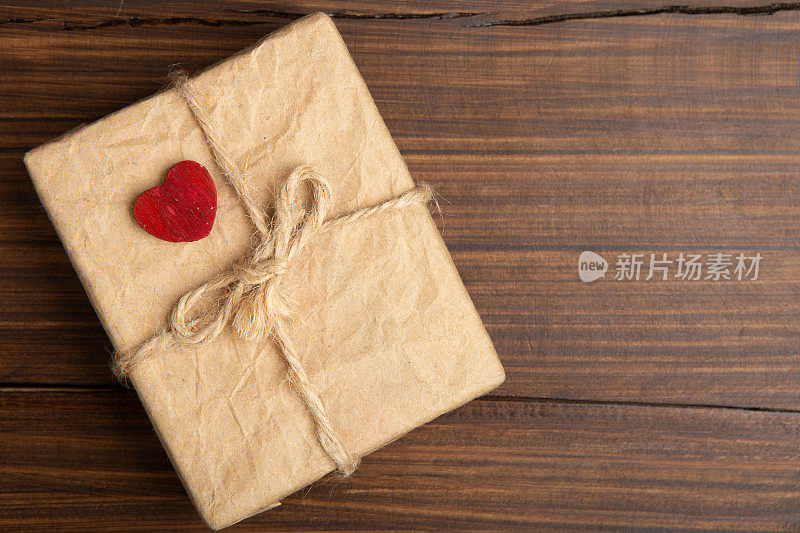 情人节问候概念。木制背景上的红色小木雕心和礼盒。情人节贺卡。