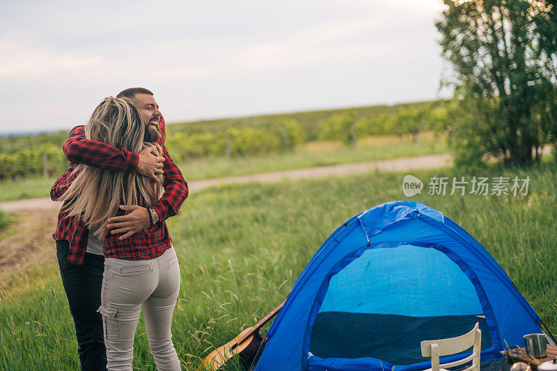 漂亮的年轻夫妇站在那里，微笑着互相拥抱