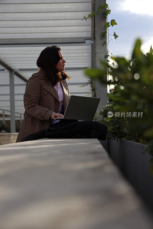 年轻女士在植物间操作笔记本电脑