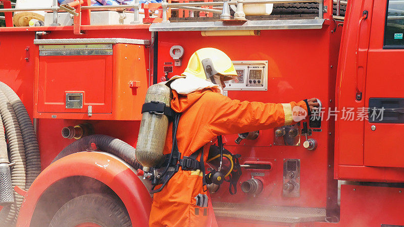 消防队员在消防车上准备灭火设备。消防队员使用消防水带、消防管、化学水泡沫喷雾灭火。消防队员戴安全帽保护