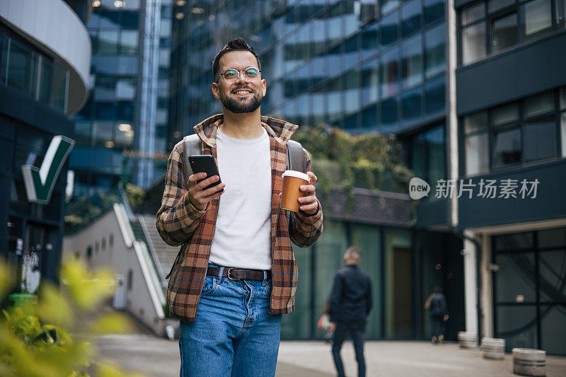 年轻的成年男子边走边打电话边喝外卖咖啡。