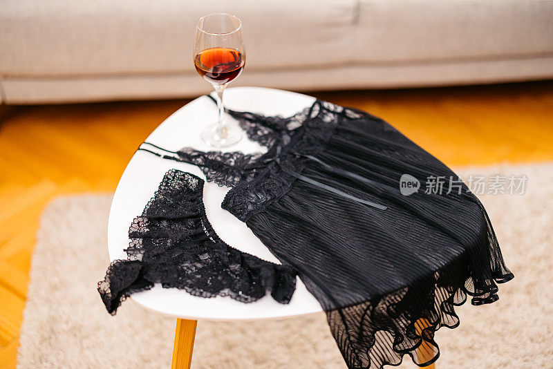 客厅的咖啡桌上有一件睡袍、一条内衣和一杯酒