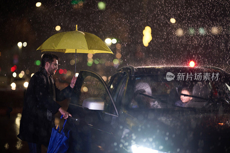 一个顾家的男人在雨天亲切地为家人开了车，给他们撑了一把伞