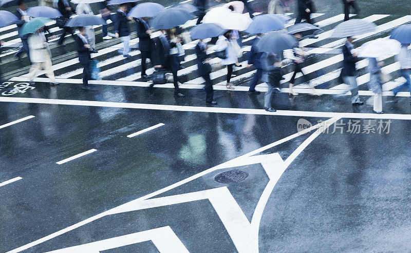 繁忙的人行横道场景在雨天与模糊运动