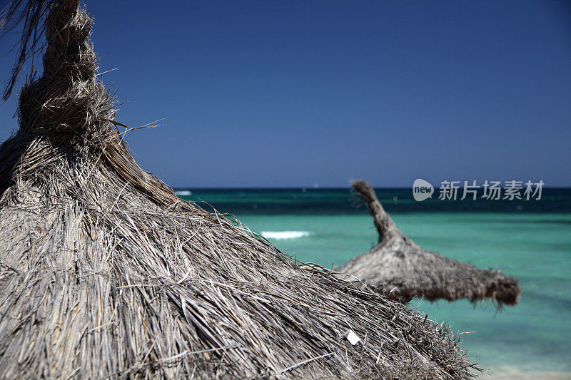 稻草沙滩阳伞和蓝绿色大海