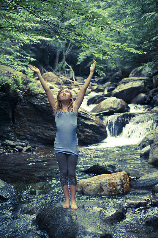 年轻女孩在瀑布中享受大自然。