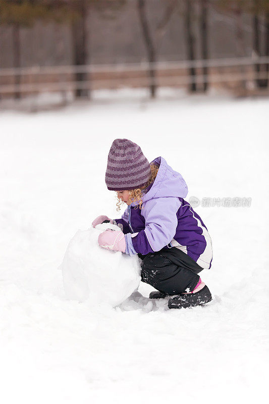 女孩为雪人滚雪球