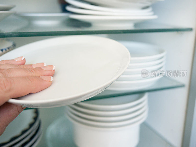 把一个干净的盘子放进碗柜里