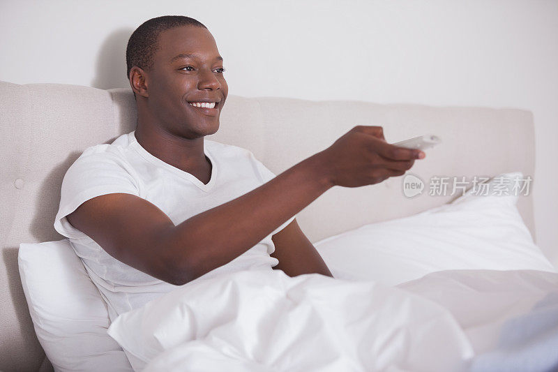男人躺在床上看电视