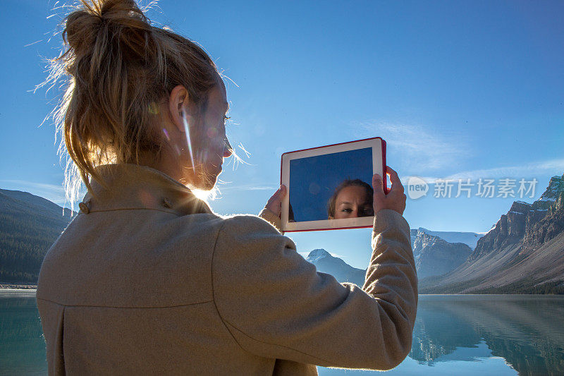 年轻女子用数码平板电脑拍摄壮观的风景