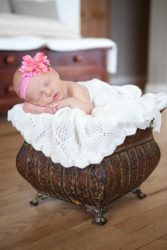 带着头巾和花睡着的新生女婴