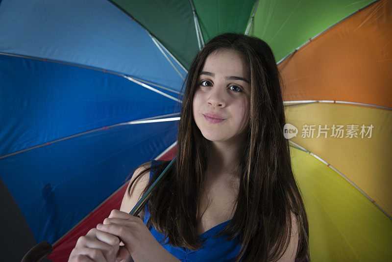 带彩虹伞的小女孩在黑色背景上