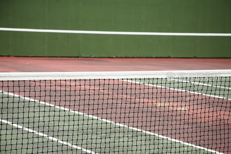 带网的红土网球场。空,空无一人。绿色的墙。