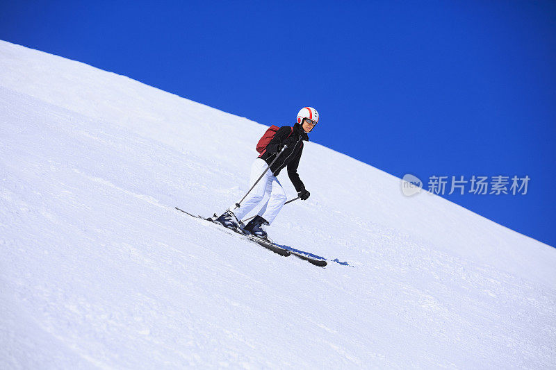 在阳光明媚的滑雪胜地滑雪的中年妇女滑雪