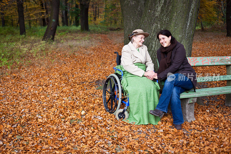 坐在轮椅上的年长女士和年轻女士坐在一起