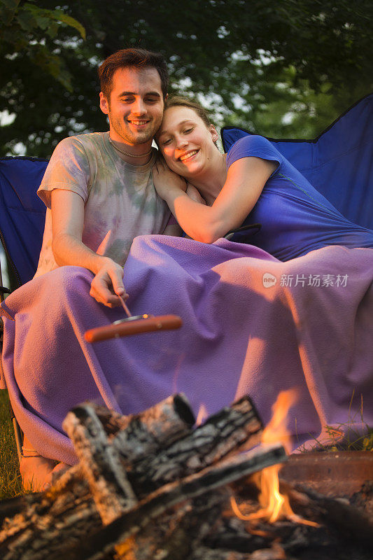 浪漫的野营夫妇在火坑营火烤热狗