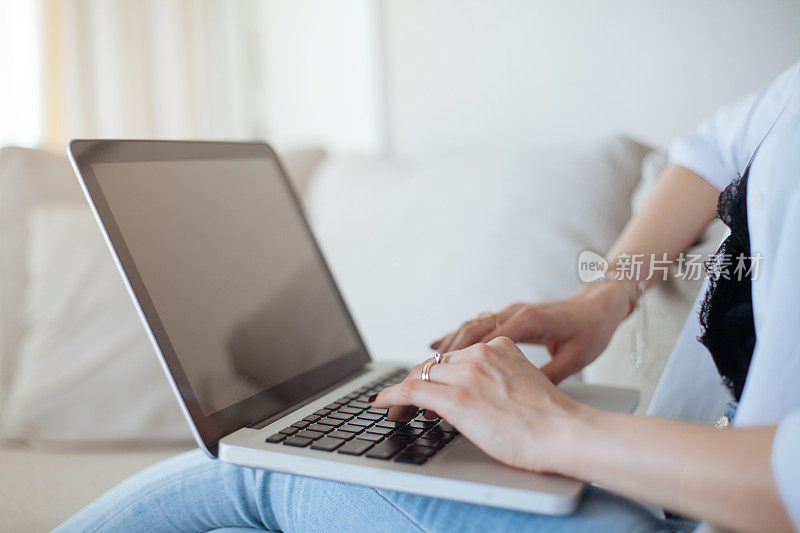 坐在沙发上玩笔记本电脑的女人