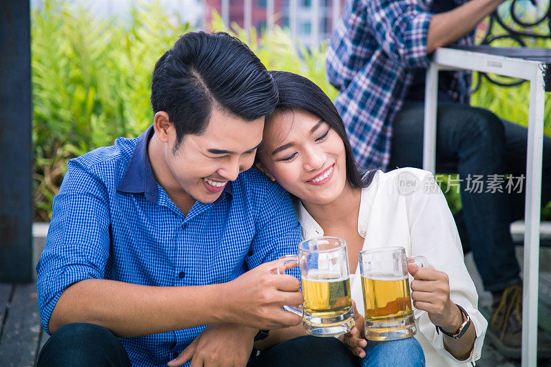 年轻的亚洲夫妇在屋顶上的派对上喝啤酒