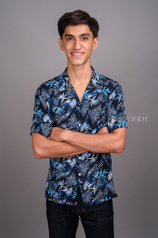 摄影棚里的年轻波斯少年穿着夏威夷衬衫，背景是灰色