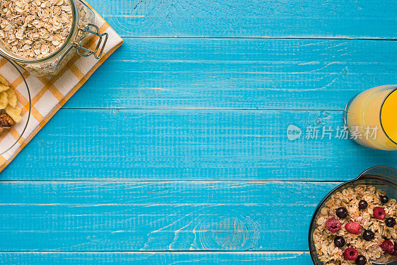 燕麦片牛奶和浆果碗和勺子在蓝色木制背景，俯视图