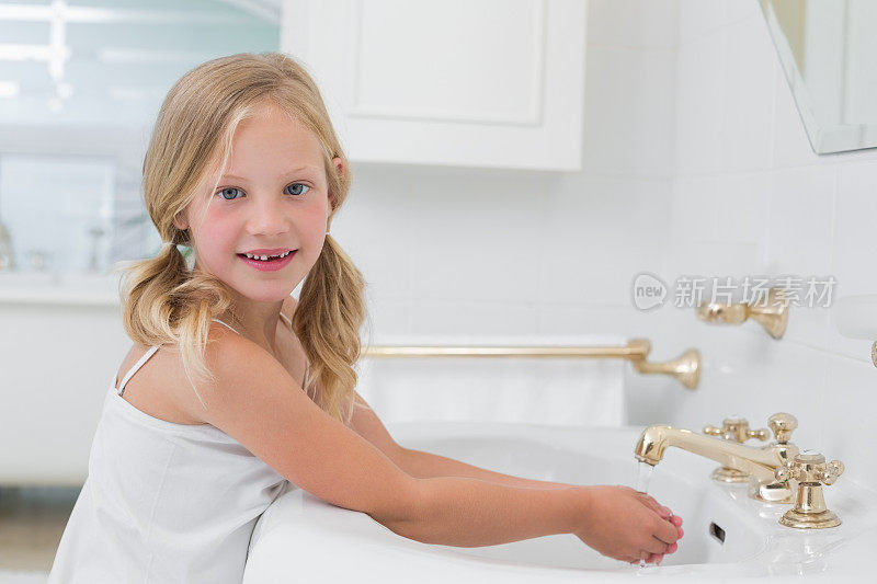 一个可爱的女孩在洗手盆洗手的肖像