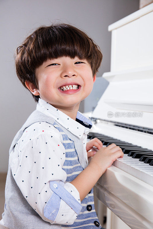 快乐的亚洲华人小男孩在家里弹钢琴