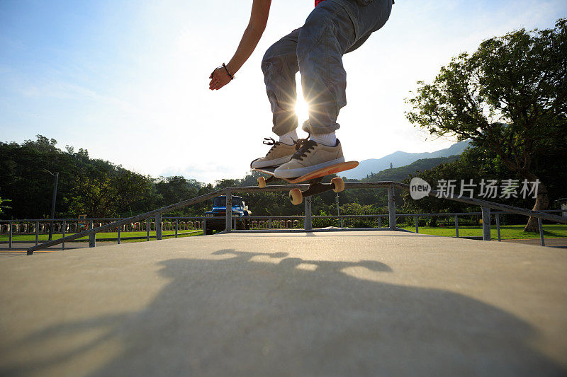 年轻的滑板运动员的腿练习奥利在滑板公园坡道