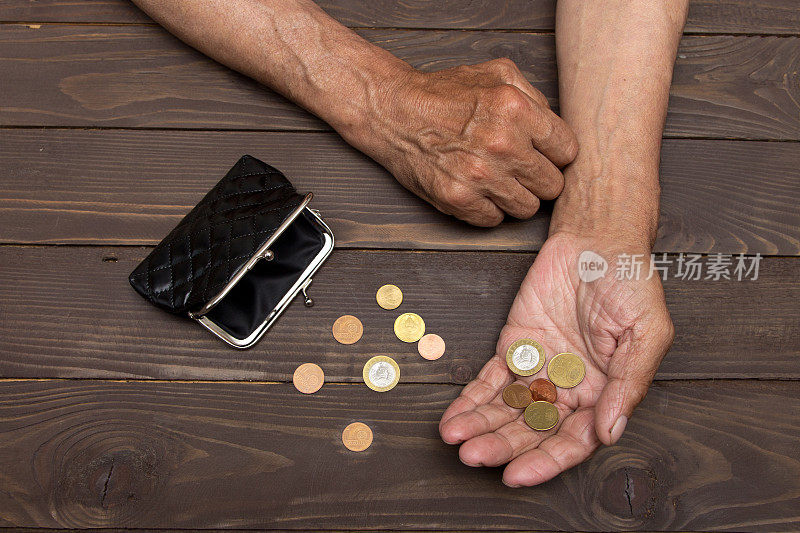 一个老人拿着一个旧硬币钱包和硬币。退休后贫困的概念。