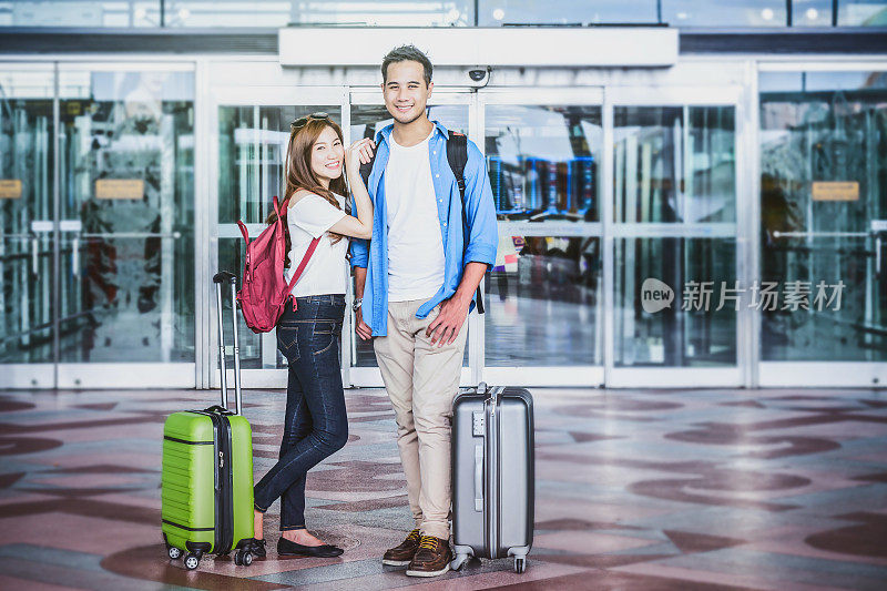 带着行李箱的亚洲夫妇在机场。带科技理念的情侣旅游交通。