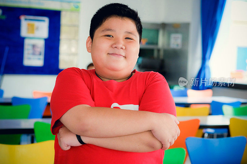 亚洲肥胖男孩站在交叉的胳膊和可爱的微笑