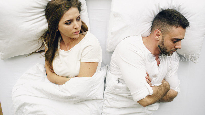 Top视图的年轻夫妇躺在床上有问题后，争吵和生气的对方在家里