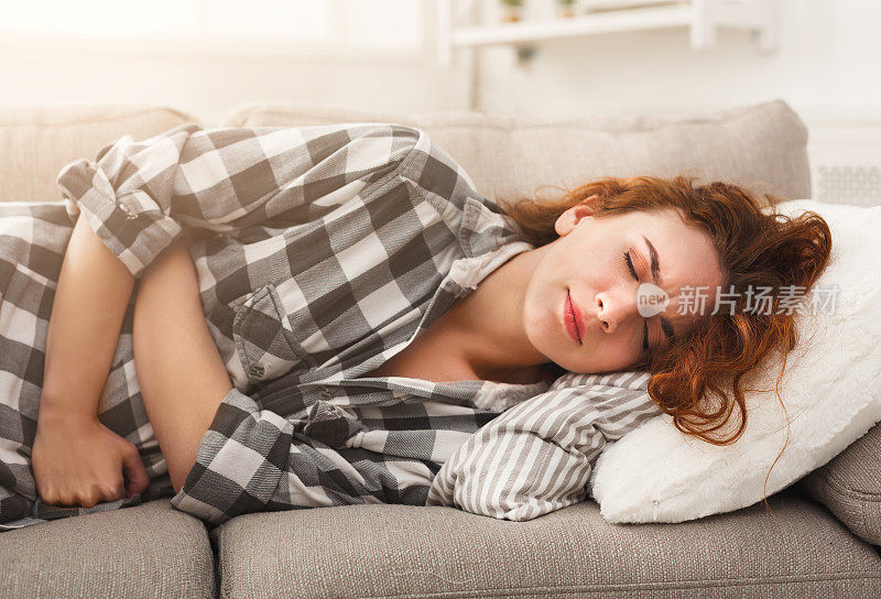 一个胃痛的小女孩躺在沙发上