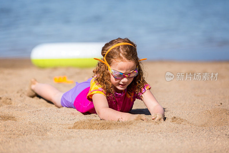 女孩躺在沙滩上玩沙子