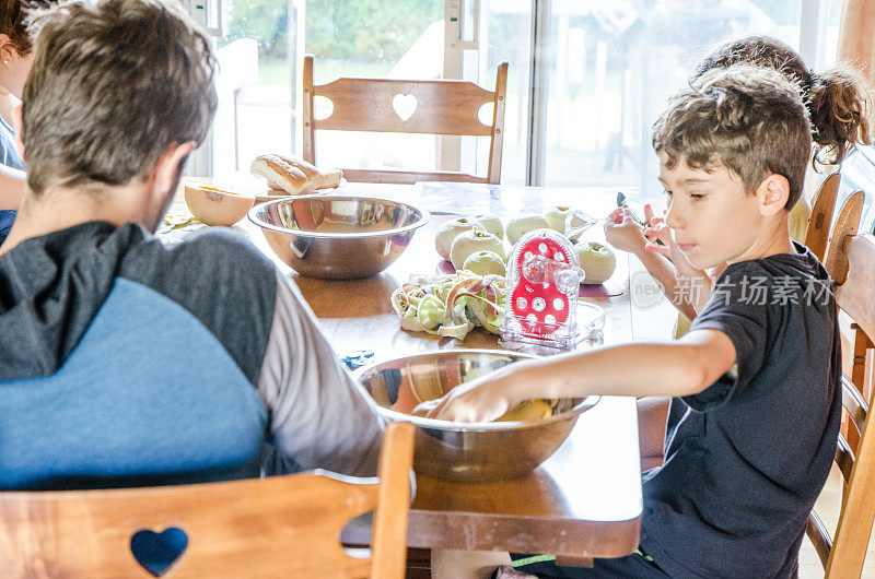 父母和孩子在餐桌上削苹果