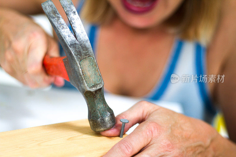 疼痛和伤害:女人用锤子击打拇指