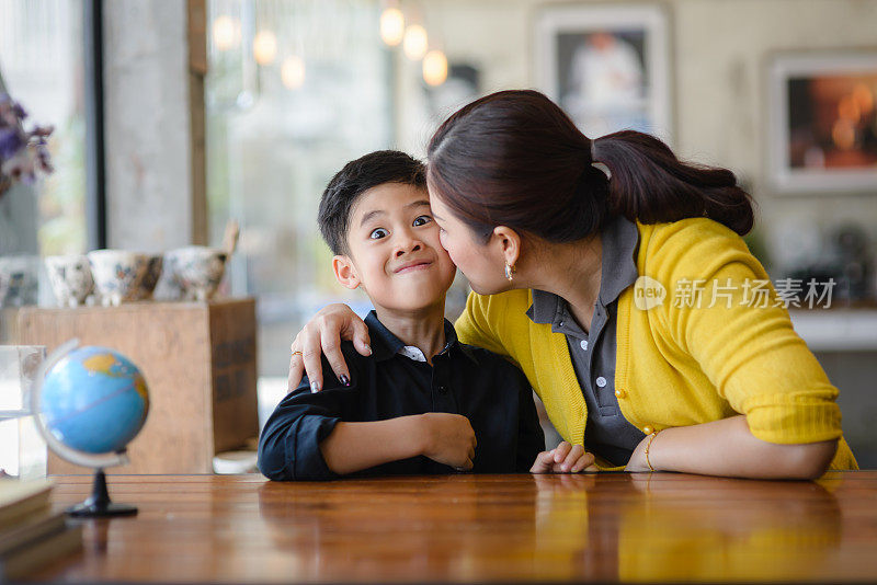 滑稽的脸男孩在亲吻他的母亲，生活方式的概念。