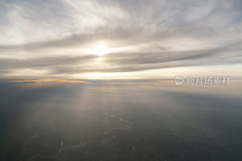 阳光从云层中闪烁，从飞机上看到在空中飞行