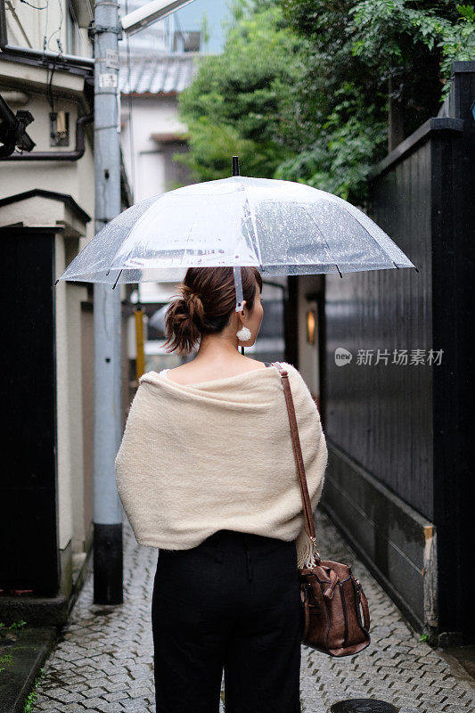 在一个雨天，在东京神乐坂传统老城的小巷里走着的女人的背影